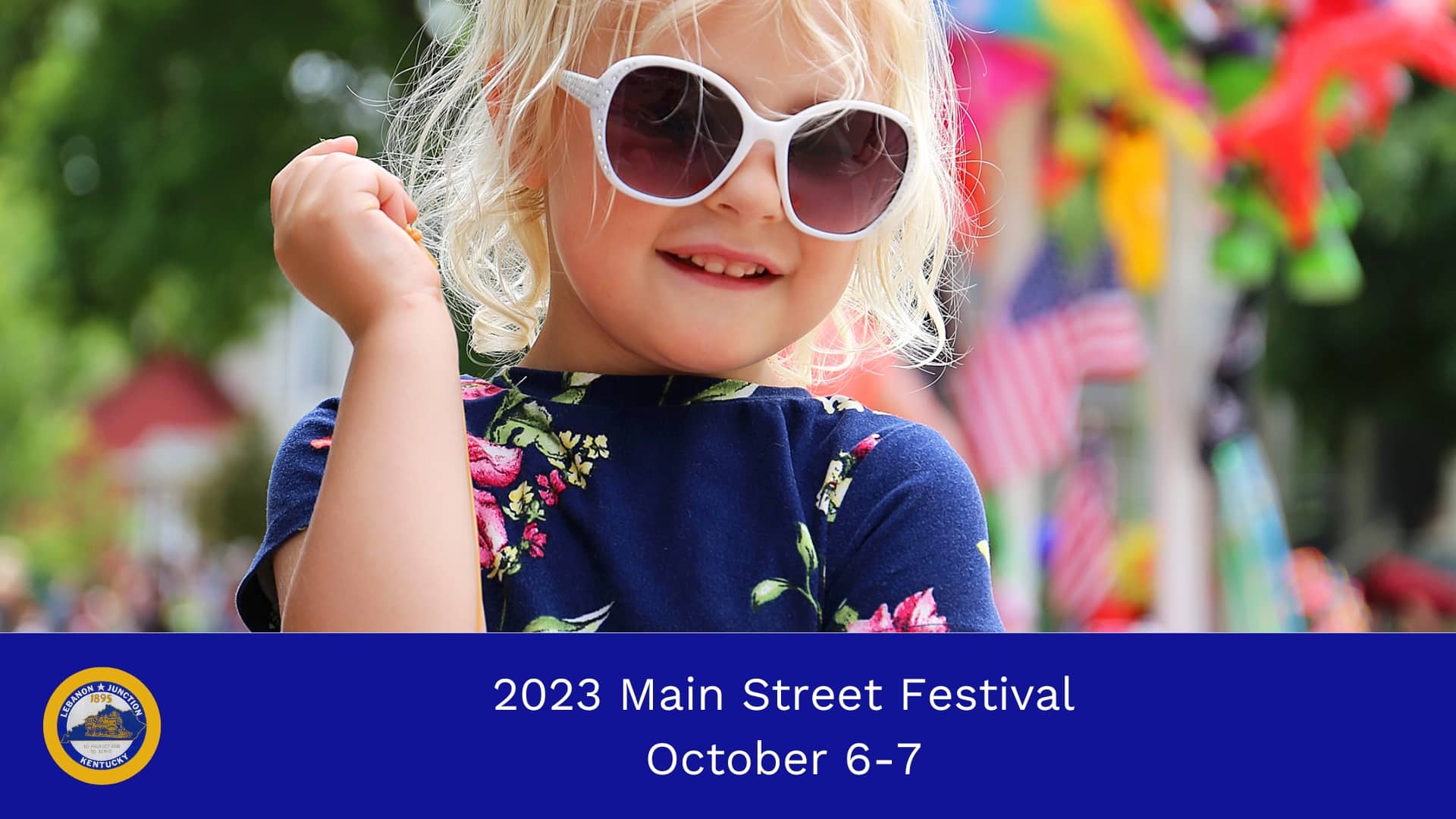 Young child wearing sunglasses with festival decor in the background